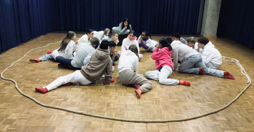 Kinder sitzen in einem Kreis aus einem Tau am Boden.
